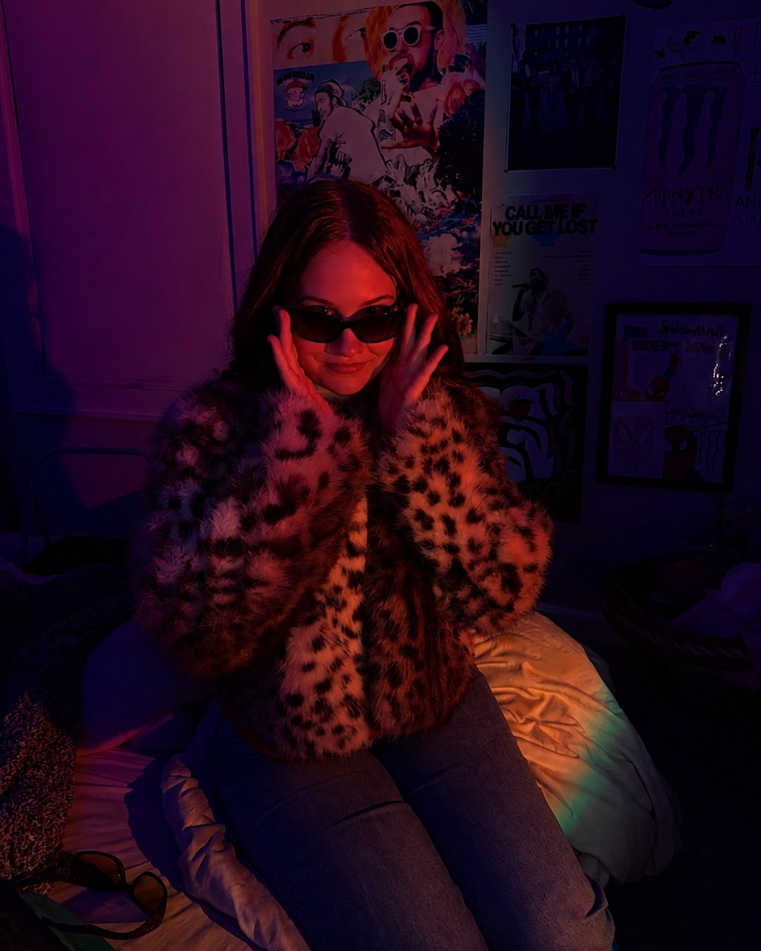 Clara in sunglasses and a leopard-print coat under red and blue lighting